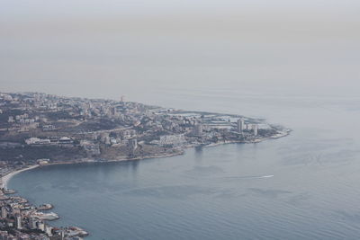 Aerial view of city by sea against sky