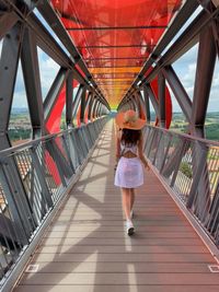 Rear view of woman walking on footbridge