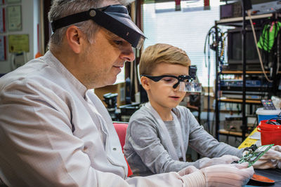 Man with boy examining computer part