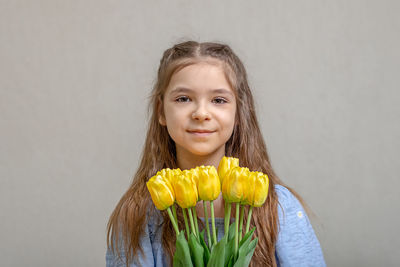 Portrait of smiling young woman against wall