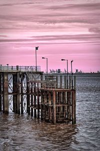 Pier over sea against sky during sunset