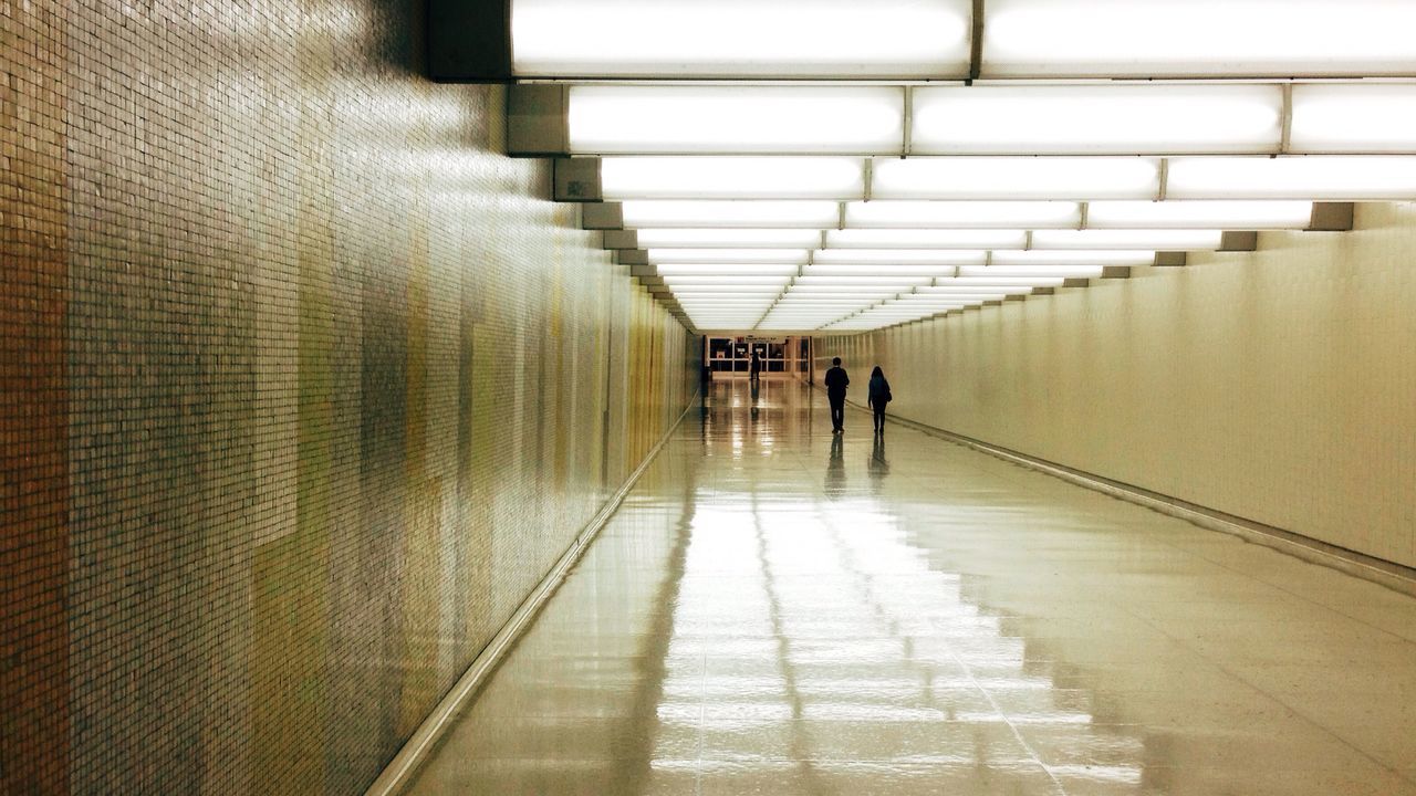 indoors, walking, architecture, men, built structure, lifestyles, full length, corridor, rear view, the way forward, person, silhouette, tunnel, ceiling, wall - building feature, leisure activity, tiled floor, flooring