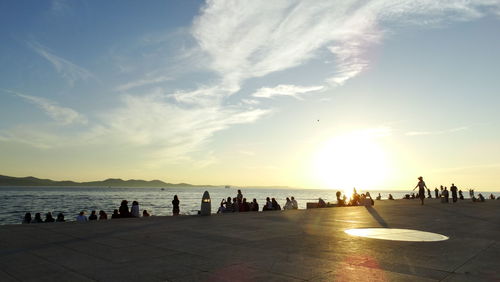 Silhouette people on beach against sky during sunset