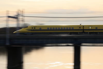 Train on bridge against sky during sunset