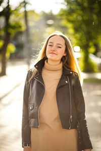 Portrait of young woman standing against trees