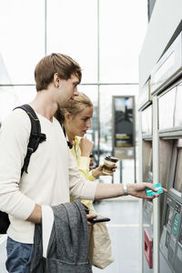 Friends using atm at railroad station