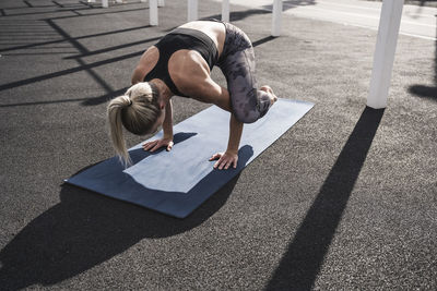 Young sportswoman practicing crow yoga pose on exercise mat