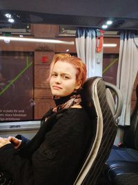 Portrait of young woman sitting on seat in bus