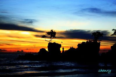 Silhouette trees by sea against sky during sunset