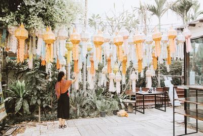 Rear view of woman touching lantern at walkway