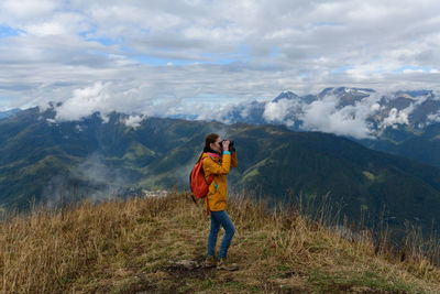 Rear view of woman standing on mountain against sky