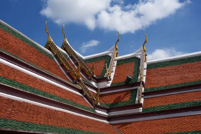 Low angle view of ornate thai temple rooftop against sky