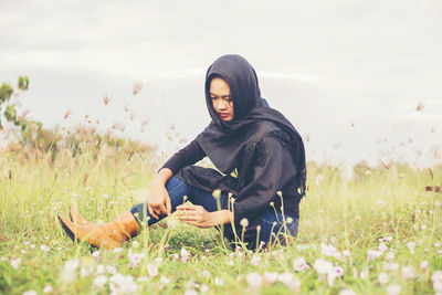 Full length of young woman sitting on field