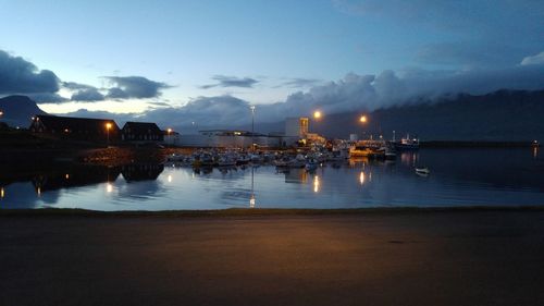 Illuminated city by sea against sky at night