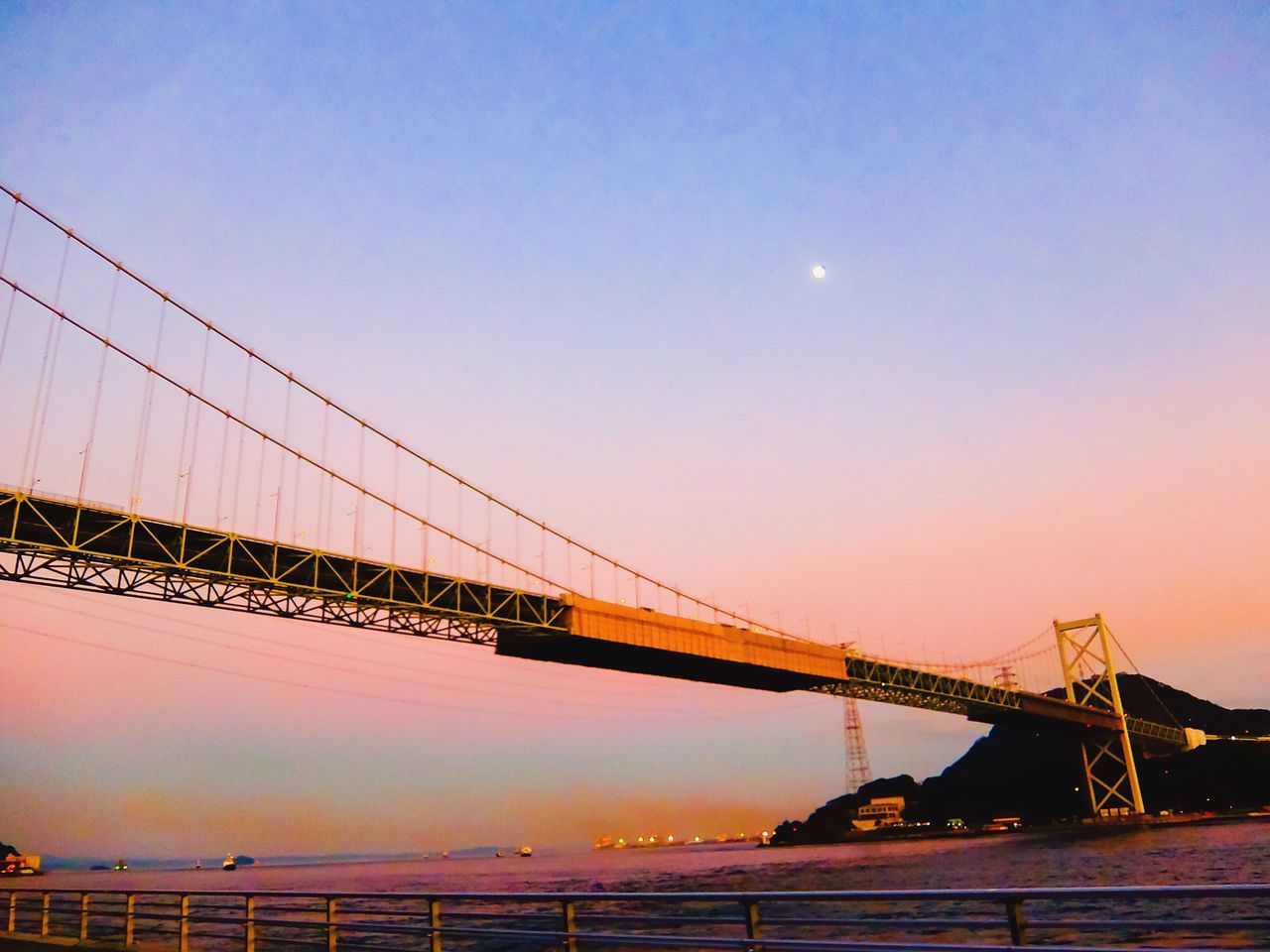 VIEW OF SUSPENSION BRIDGE AGAINST SKY DURING SUNSET