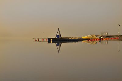 Lifeguard hut in sea against clear sky during sunset