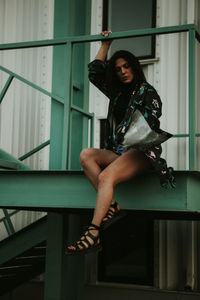 Portrait of young woman sitting on railing