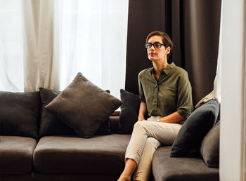 Mid adult woman sitting on sofa at home