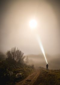 Man standing on field against bright sun