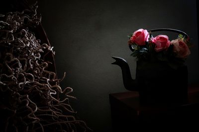 Close-up of rose in vase on table against wall