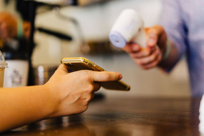 Midsection of man using scanner with customer at his shop