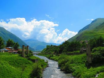 Scenic view of green landscape and mountains against sky