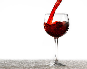 Close-up of wineglass on glass against white background