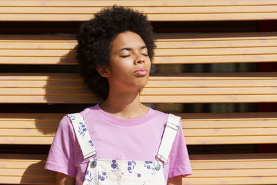 Portrait of young woman standing against corrugated iron