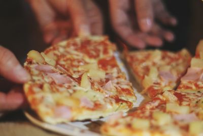 Close-up of hand holding pizza