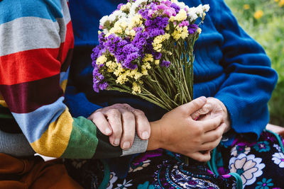 Midsection of man holding flower bouquet