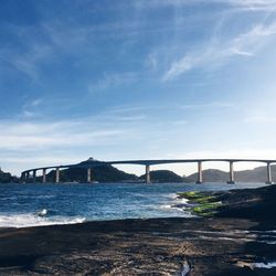 Bridge over river against cloudy sky