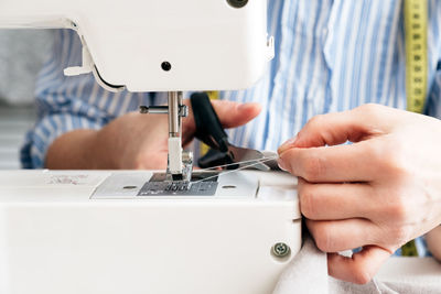 Midsection of craftswoman cutting thread on machine at workshop