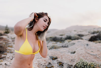 Young woman standing on beach against sky