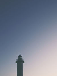 Low angle view of lighthouse by building against clear sky