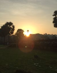 Silhouette trees on field against sky during sunset