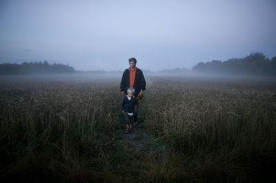 Mother walking with son through foggy meadow