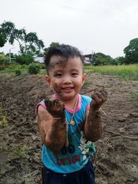 Portrait of smiling boy standing on dirt road