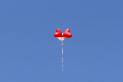 Three helium balloons flying against clear sky