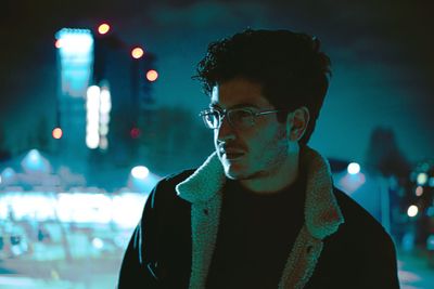 Portrait of young man looking away at night