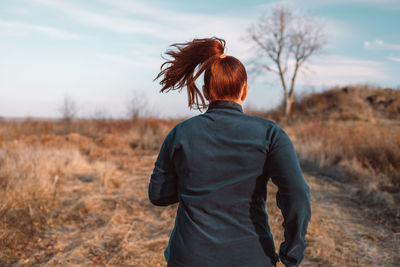 Rear view of woman standing on field