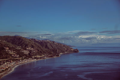 Scenic view of sea by mountain against sky