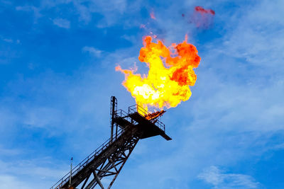 Low angle view of fire against blue sky