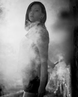 Side view portrait of young woman with smoke standing at park