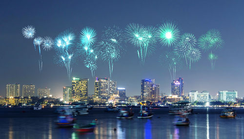 Firework display over illuminated buildings in city at night