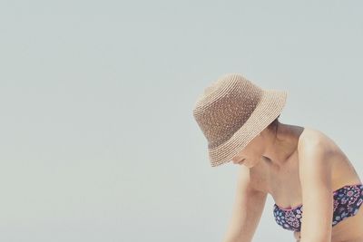 Midsection of shirtless young woman against clear sky