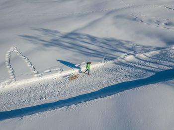 High angle view of woman pulling sleigh while walking on snow covered land