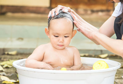 Shirtless baby boy sitting in tub