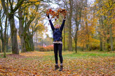 Young woman throwing leaves in a heart shape in the air