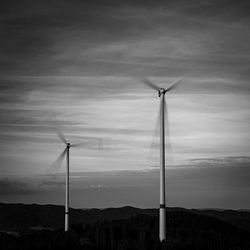 Wind turbines on field against sky