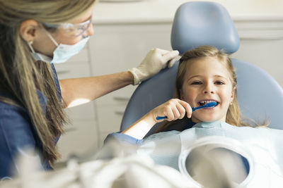 Girl brushing teeth in medical clinic by dentist